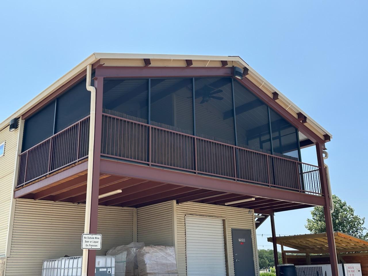 Exterior view of the Kai-Simone Winery screened balcony on the second floor with metal railing and blue sky